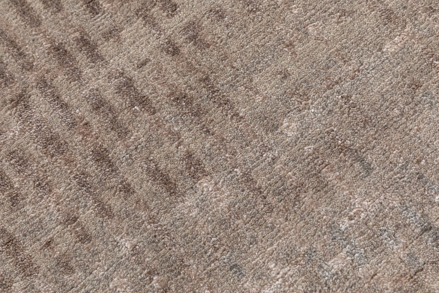 A close-up texture shot of a brown and beige patterned carpet or fabric with a heathered, woven appearance.Rust colored hand knotted 4x5 ft rug made in bhadohi