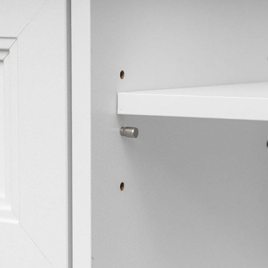 Close-up detail of a white shelf mounted on a white cabinet wall, showing a silver metal shelf pin and pre-drilled mounting holes.