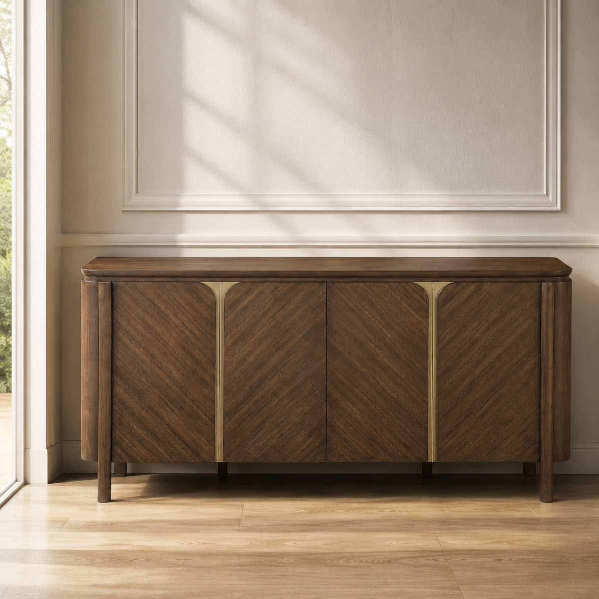 A mid-century modern wooden sideboard with chevron grain patterns and brass-finished vertical dividers, positioned against a beige wall with decorative molding and soft window shadows.
