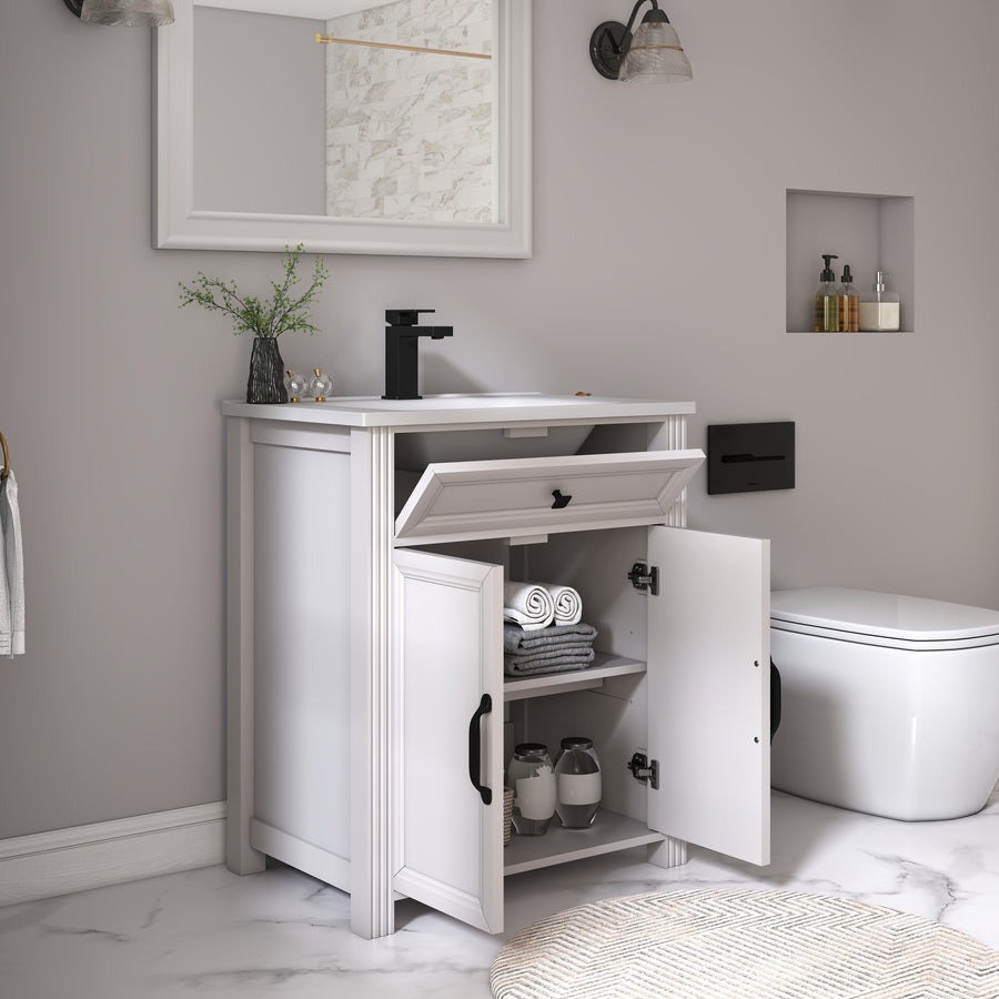 A white bathroom vanity cabinet with an open lower door showing towels and jars, set beside a white toilet in a modern bathroom with gray walls and marble flooring.
