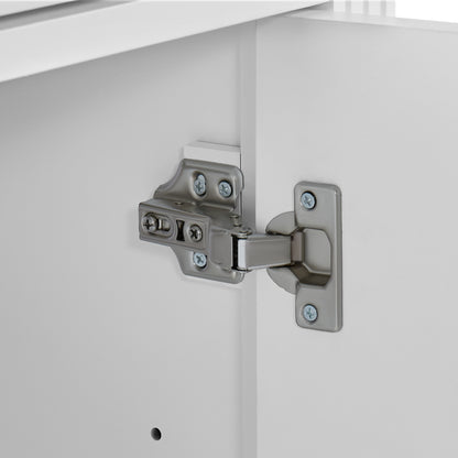Close-up of a silver metal cabinet hinge mounted on a white cabinet door, with part of the cabinet frame visible.