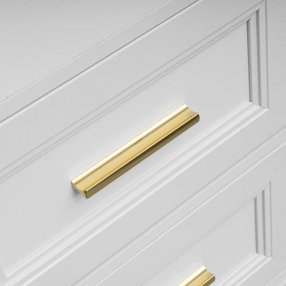 A close-up of a white paneled cabinet or drawer featuring a modern, slim rectangular brass pull handle.