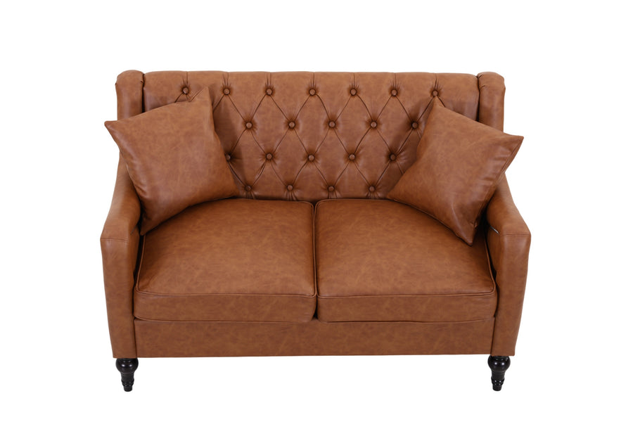 A brown faux leather loveseat sofa with a tufted diamond pattern on the backrest, two matching throw pillows, and dark turned wooden legs, shown against a plain white background. light brown loveseat