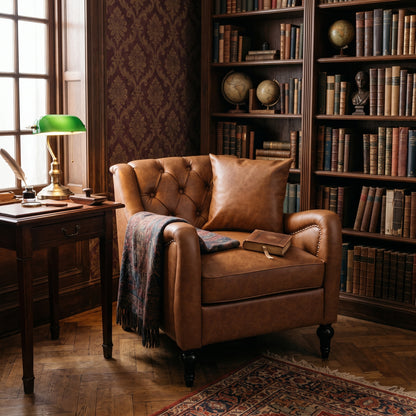 A classic brown leather Chesterfield armchair in a cozy, vintage-filled study room with bookshelves, a green desk lamp, and a patterned throw blanket. light brown solo 