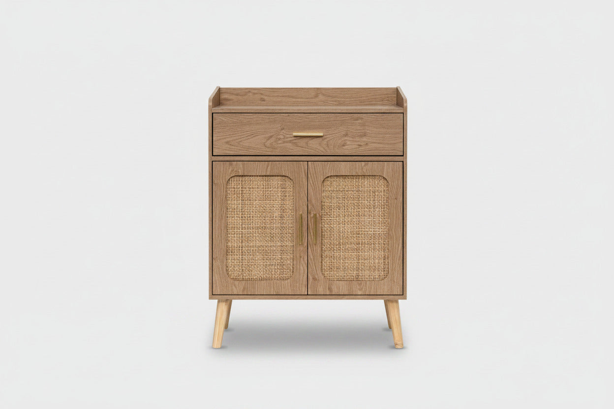 A mid-century modern wooden cabinet with a single drawer and two cane-embossed doors, featuring light wood legs and brass handles, shown on a plain natural background.