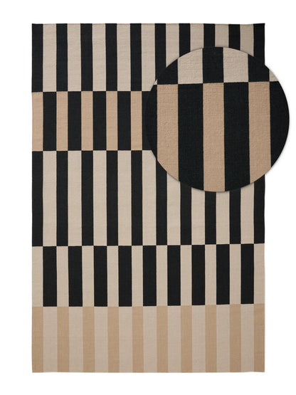 A rectangular area rug with a geometric pattern of black and beige vertical stripes and blocks, shown flat against a white background with a circular inset detail of the fabric texture. Hand made rugs