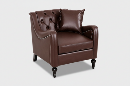 A classic Chesterfield-style armchair upholstered in dark brown faux leather, featuring a tufted button backrest, rolled arms with nailhead trim, and dark turned legs, shown with a matching throw pillow on a white background. Dark Brown solo

