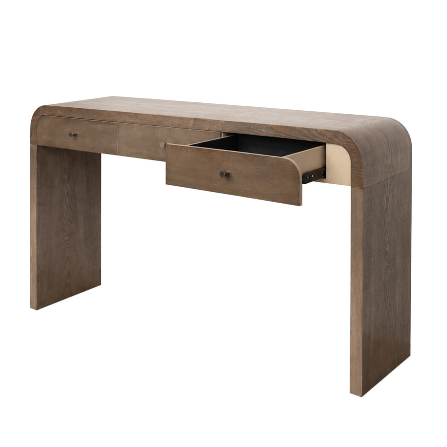 A modern wooden console desk with a curved top and legs, featuring a medium brown wood finish and an open drawer showing a black interior, set against a plain white background.