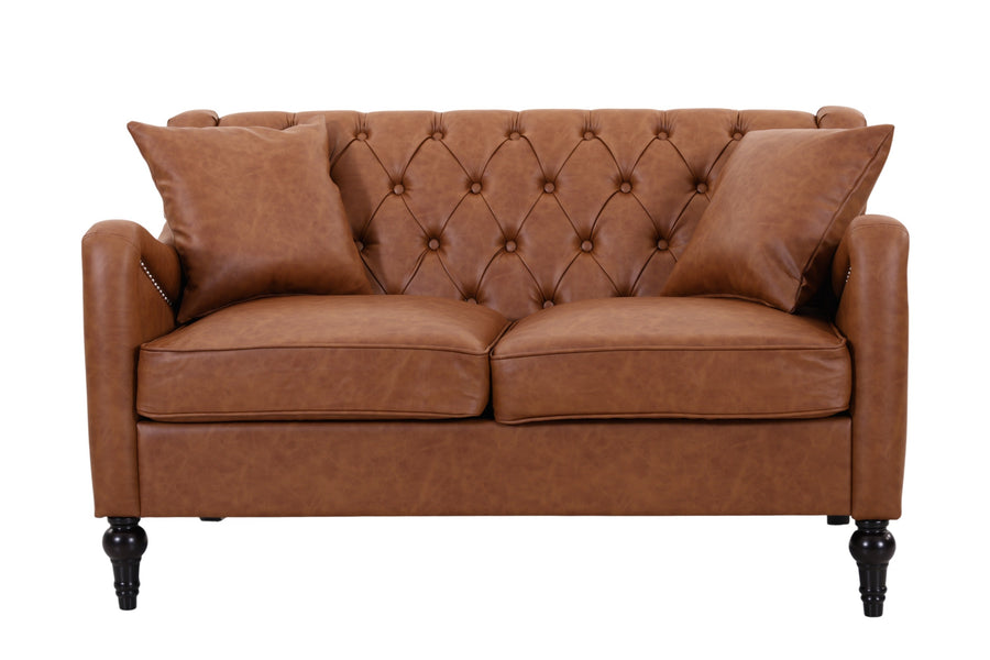 A brown leather loveseat sofa with a tufted button design on the backrest, two matching throw pillows, and dark turned wooden legs, shown against a plain white background. light brown loveseat