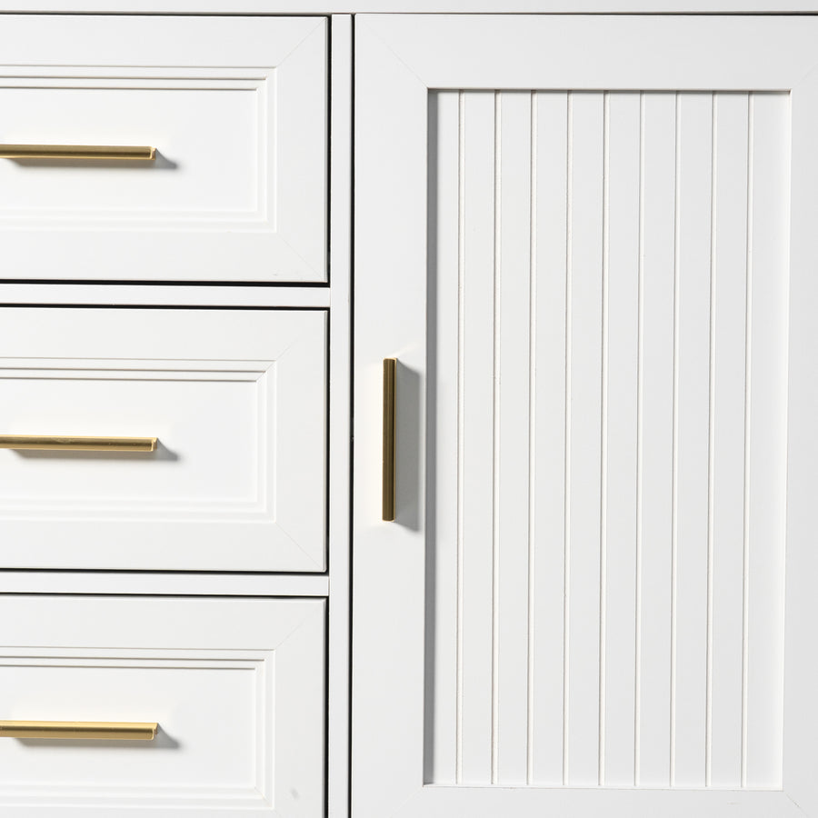 Close-up of a white cabinet with a vertical beadboard door panel and a slim vertical gold handle, next to white drawers with horizontal gold handles.