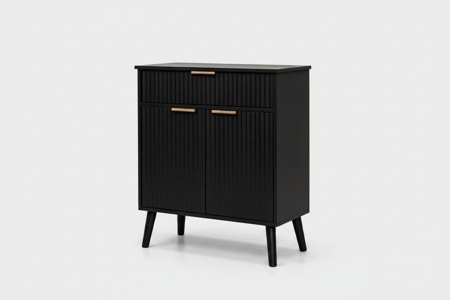 A modern black cabinet with a ribbed vertical texture, featuring two drawers on top and two doors below, accented with slim gold handles and supported by tapered legs, shown against a light gray background.