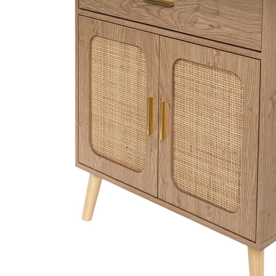 Close-up of a natural wooden cabinet with two doors featuring woven cane panels, gold-toned handles, and tapered wood legs on a background.
